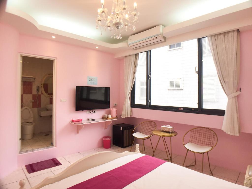 a pink bedroom with a bed and two chairs at Hualien Dawan B&amp;B in Ji&#39;an