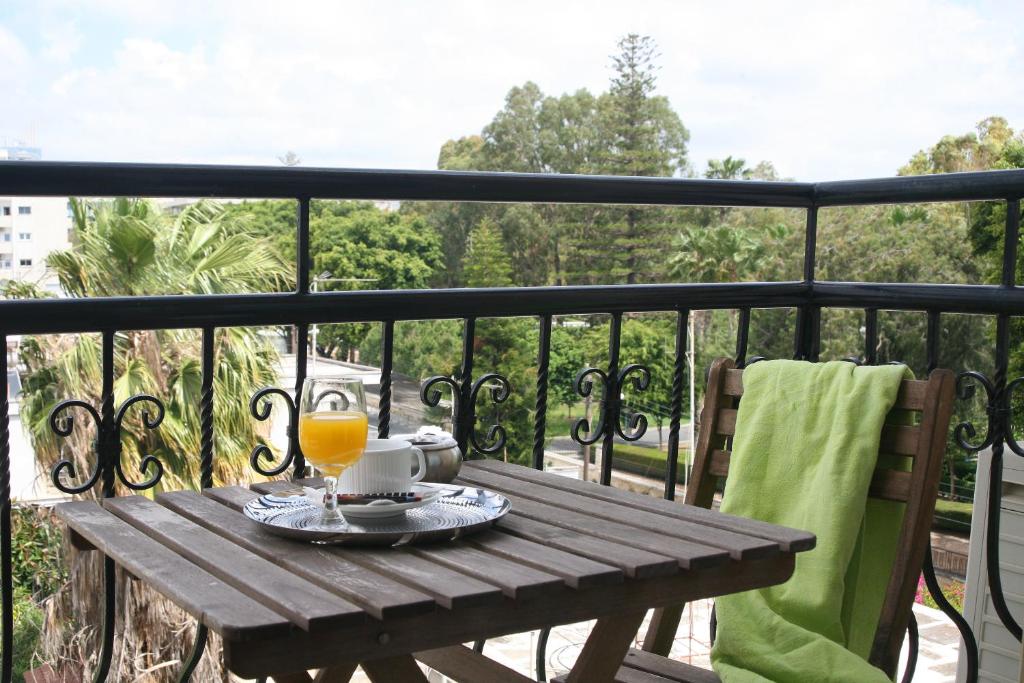 a wooden table with a glass of orange juice on a balcony at Chrielka Hotel in Limassol