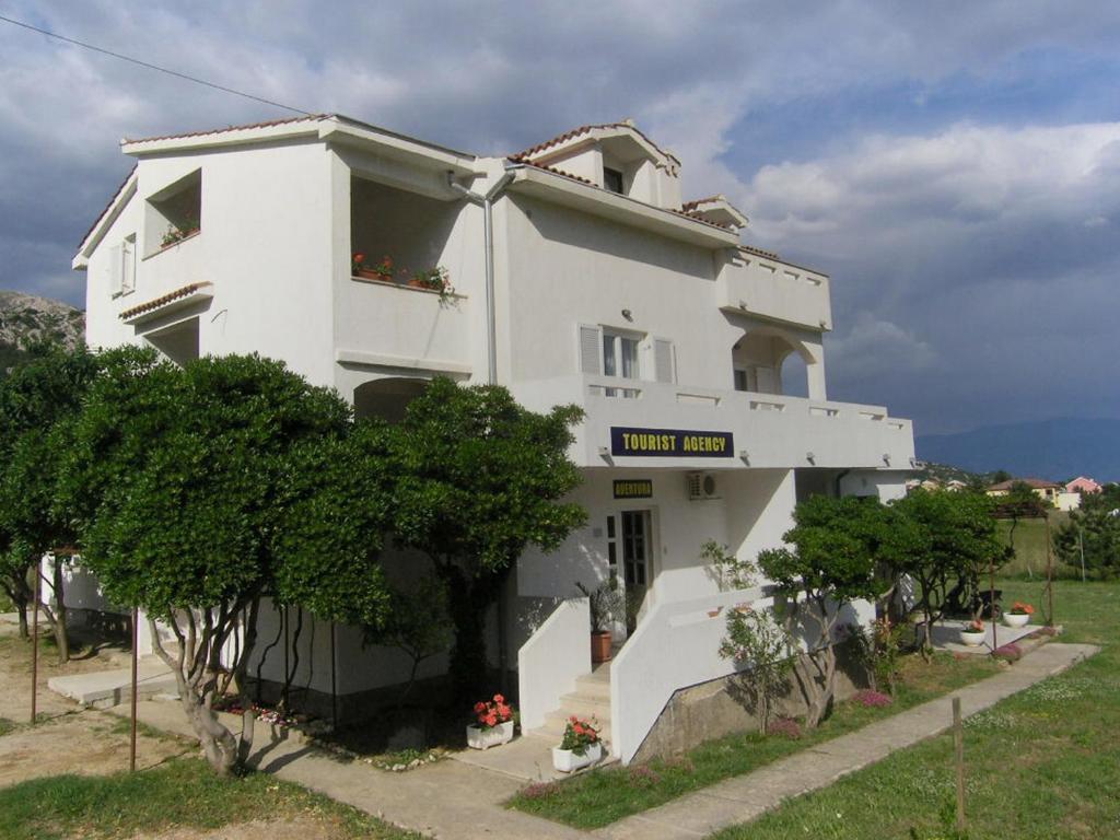 a white building with a sign in front of it at Apartments GORDANA Baska for relaxing holidays in Baška