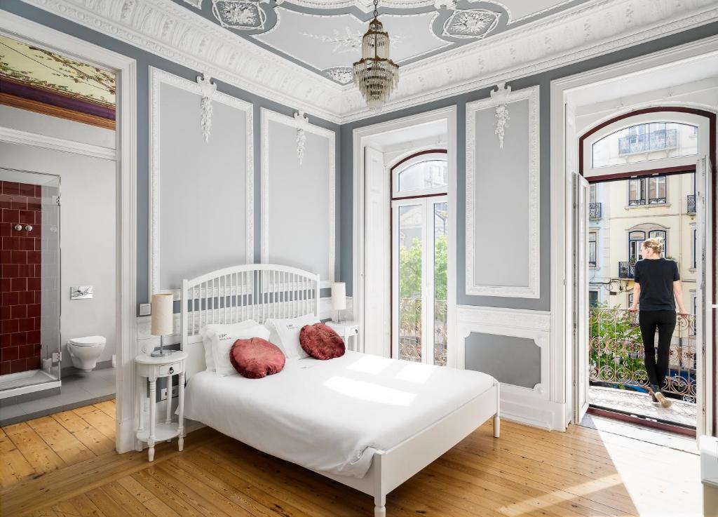 a white bedroom with a white bed and a window at O Jardim da Tessa in Lisbon