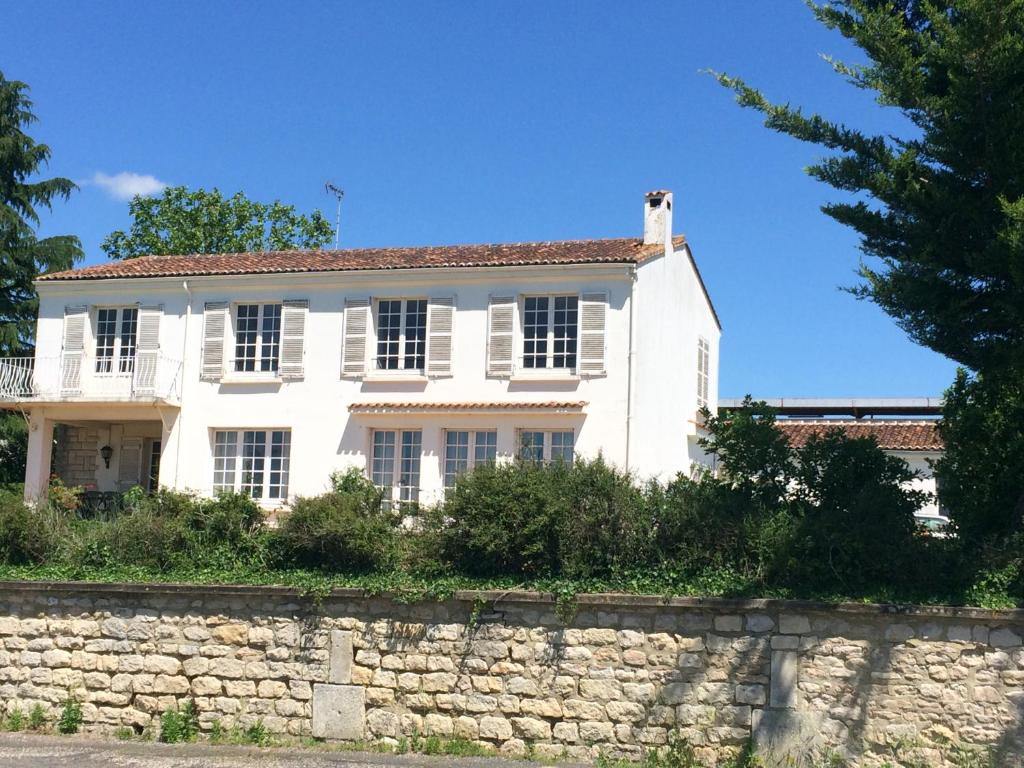 uma casa branca no topo de uma parede de pedra em La Maison Blanche em Saint-Jean-dʼAngély