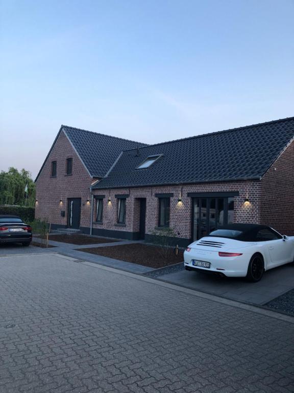 een witte auto geparkeerd voor een bakstenen huis bij BEe HOME - Urlaubs und Business Loft in Kevelaer