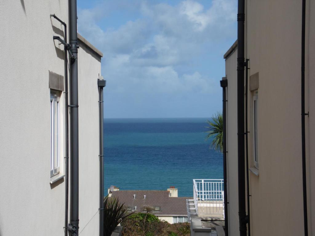 a view of the ocean from between two buildings at Soft Rock Apartment in Carbis Bay