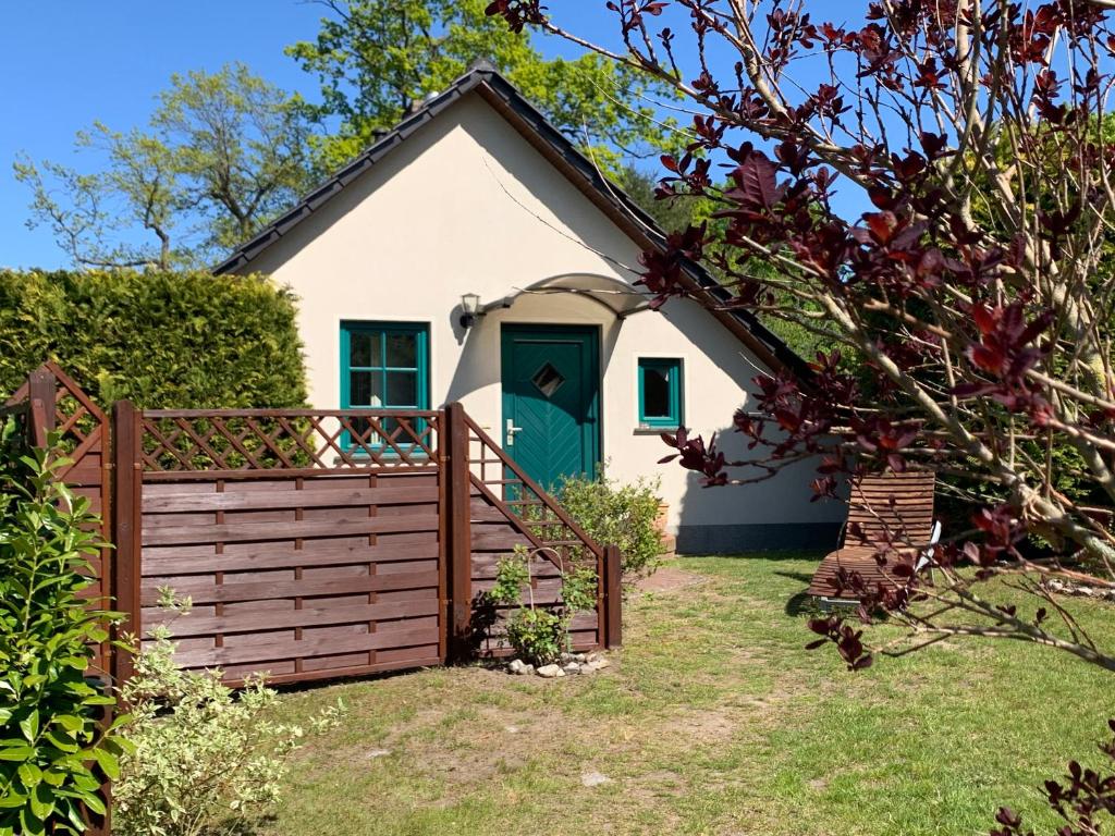a cottage with a green door and a fence at „Rentmeisterhaus Basedow“ in Basedow
