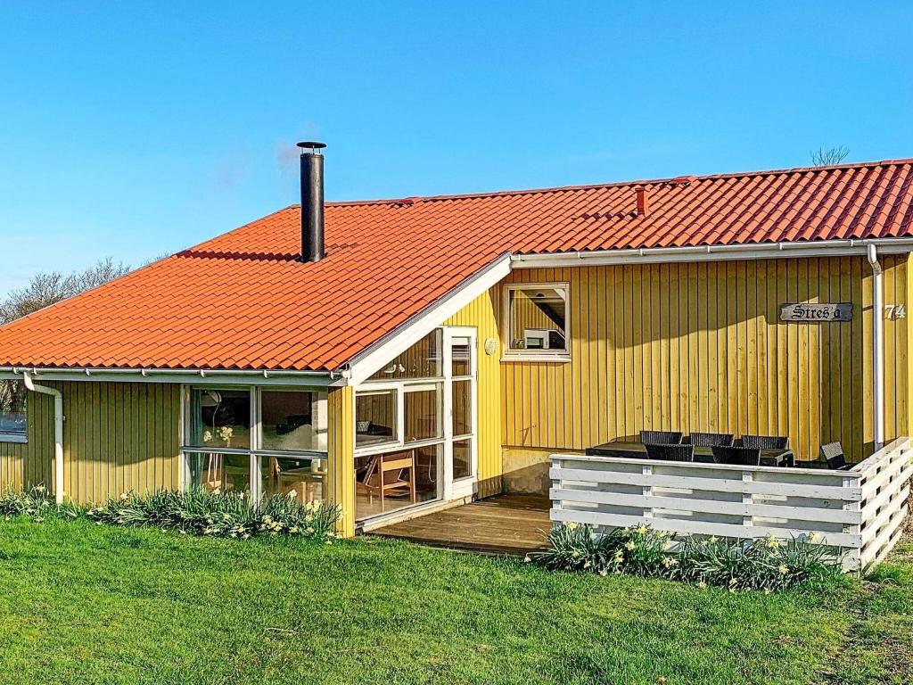 a yellow house with an orange roof and a deck at 6 person holiday home in Hemmet in Hemmet