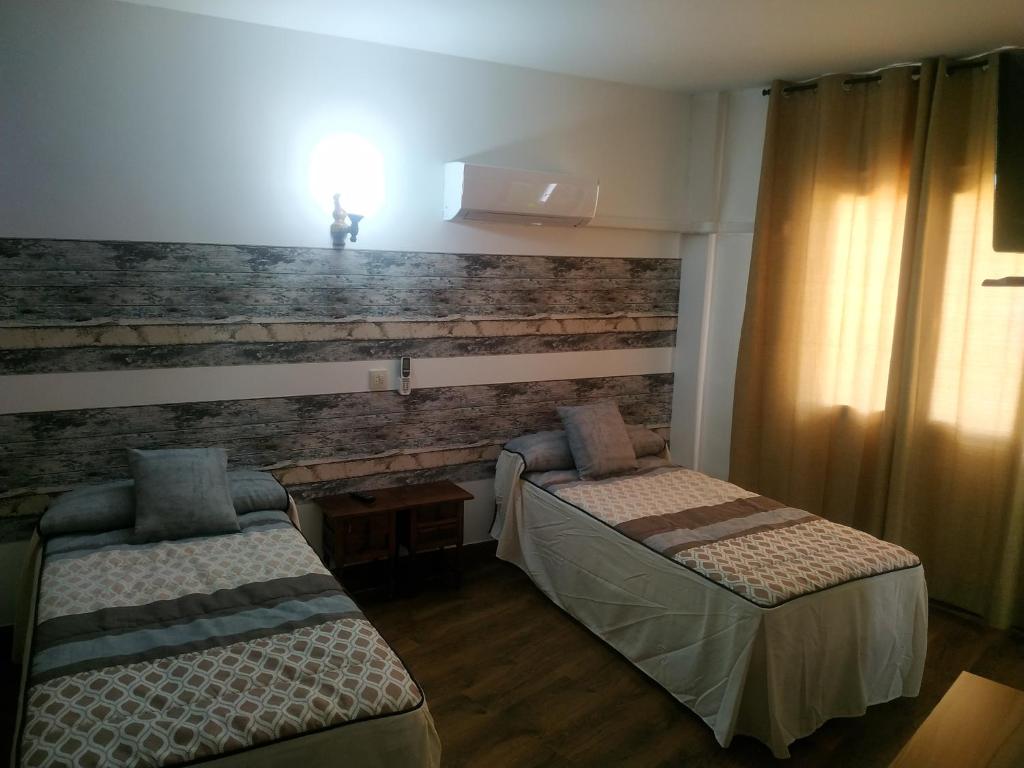 a room with two beds and a brick wall at Hostal El Rincón - Casa Marcos in Yepes