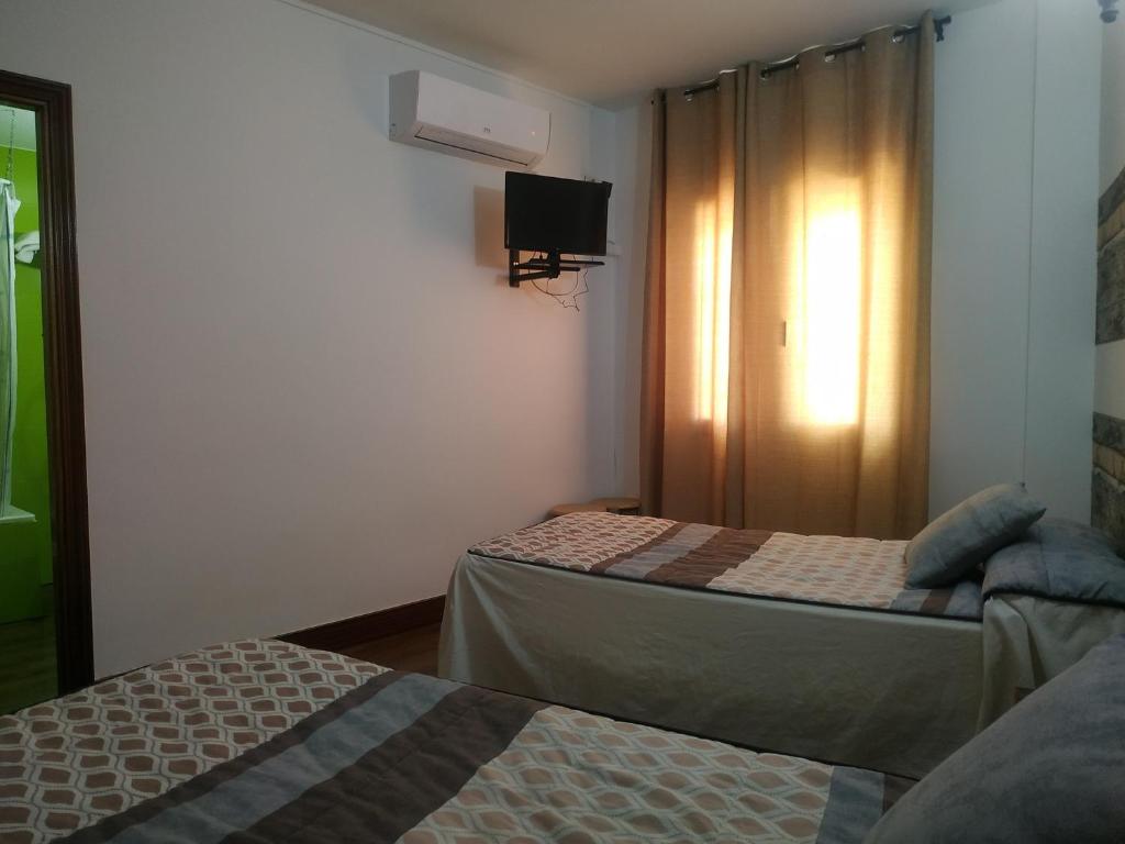 a hotel room with two beds and a tv at Hostal El Rincón - Casa Marcos in Yepes