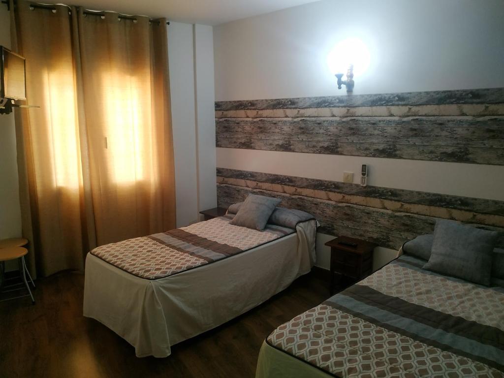 a bedroom with two beds and a brick wall at Hostal El Rincón - Casa Marcos in Yepes