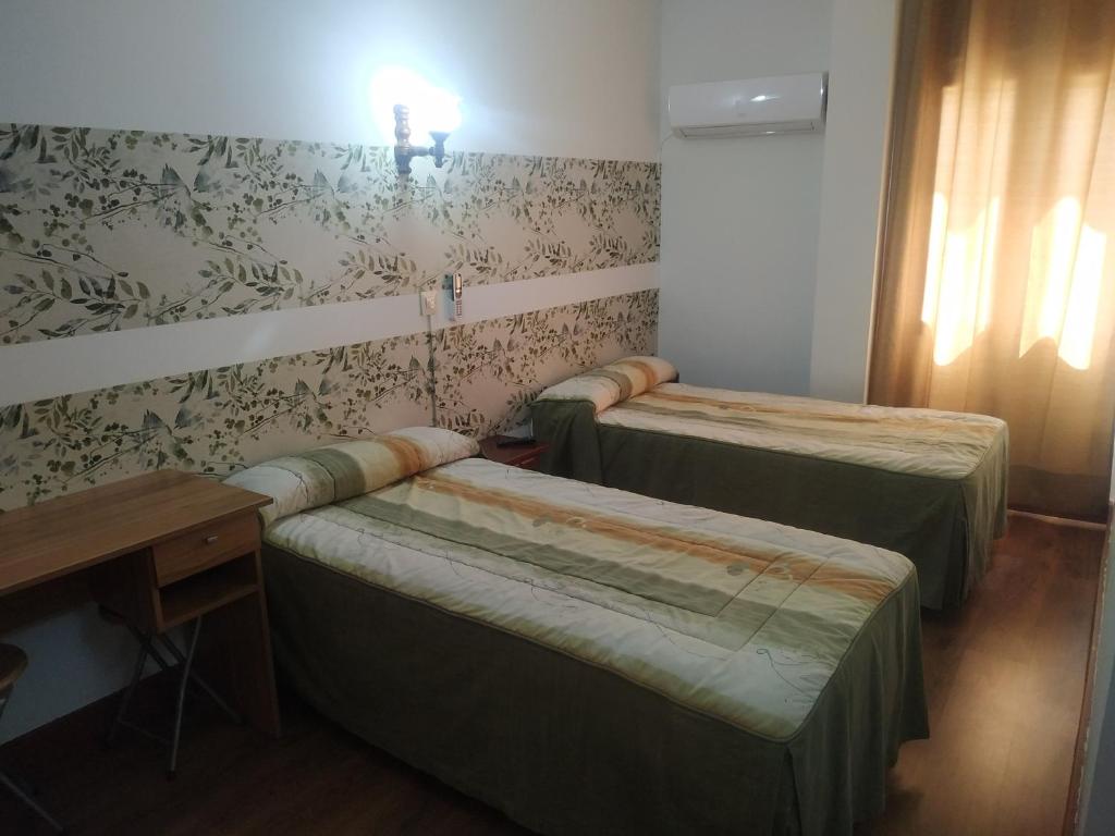 a room with two beds and a table and a desk at Hostal El Rincón - Casa Marcos in Yepes
