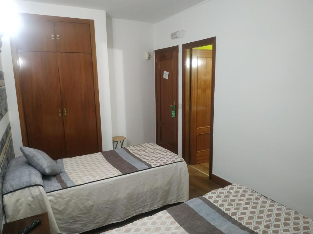 a bedroom with two beds and a closet at Hostal El Rincón - Casa Marcos in Yepes