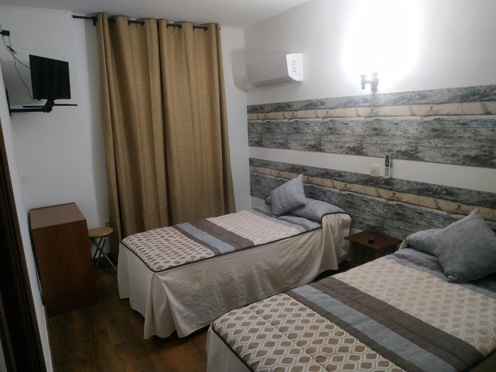 a room with two beds and a brick wall at Hostal El Rincón - Casa Marcos in Yepes