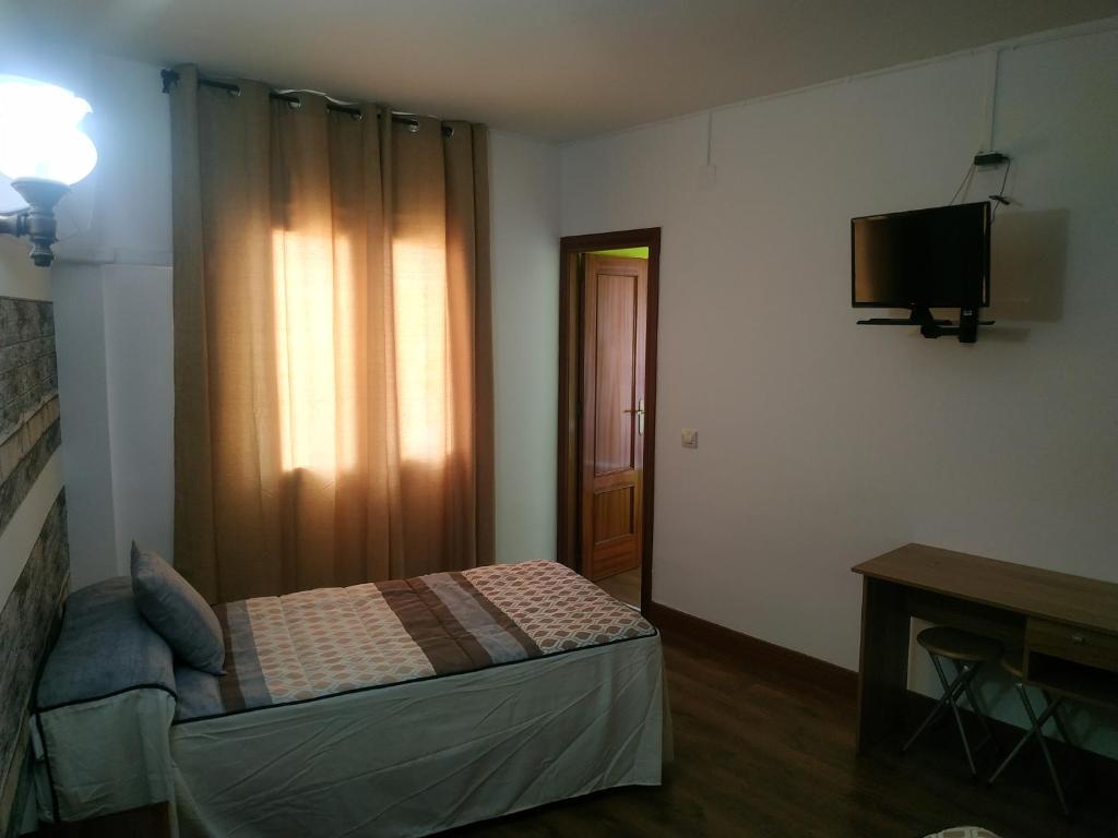 a small bedroom with a bed and a television at Hostal El Rincón - Casa Marcos in Yepes