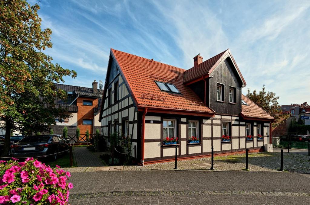 a black and white house with a red roof at Chata Rybacka Saule in Ustka