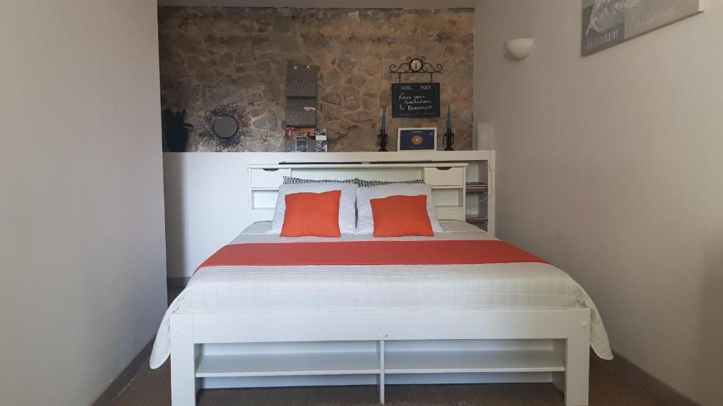 a bedroom with a white bed with two orange pillows at chambre cocoon in Roquemaure