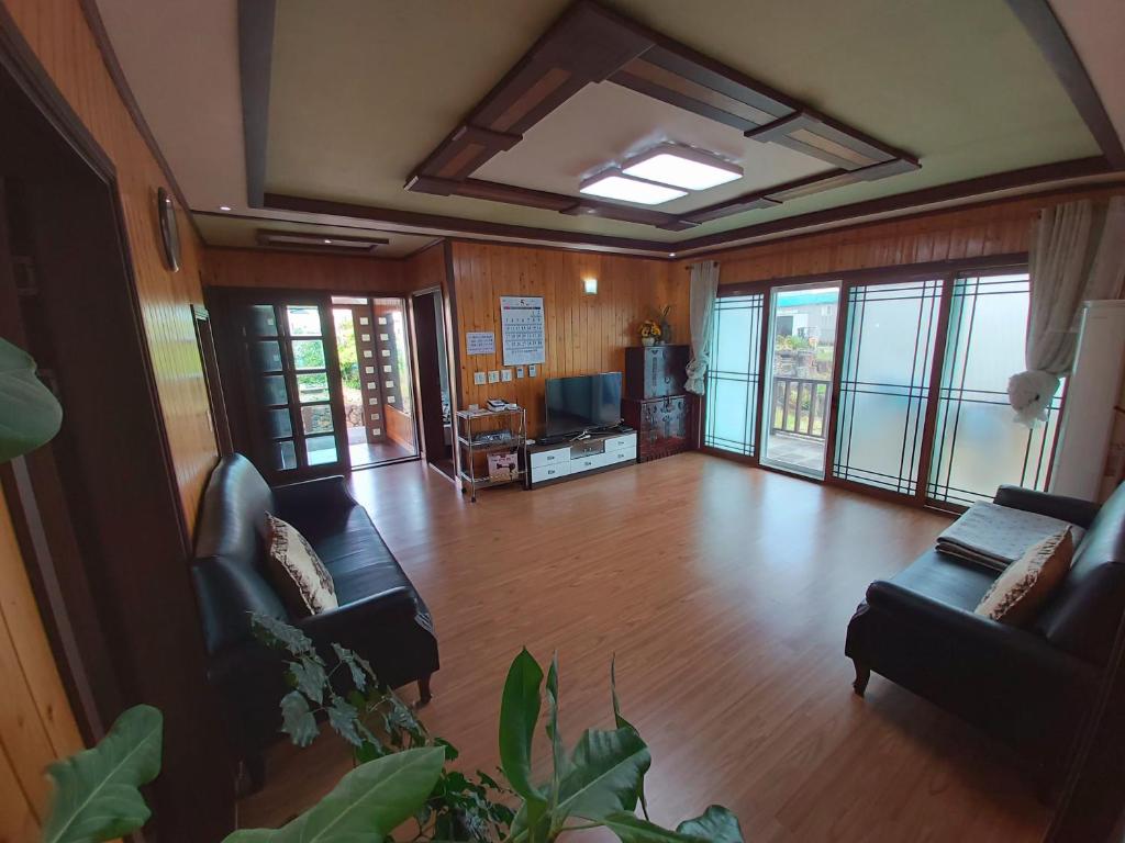 an empty living room with couches and a television at Feeling Good House in Jeju