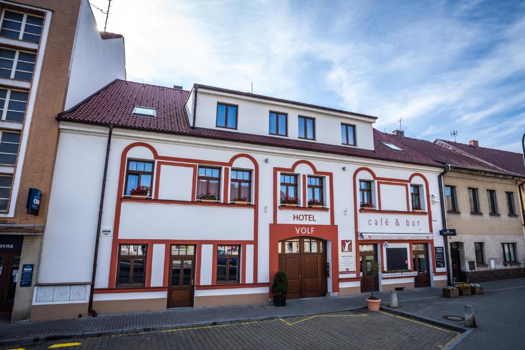 un edificio blanco con adornos rojos en una calle en Hotel Volf, en Přeštice