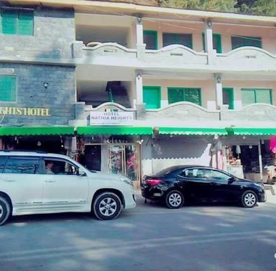 twee auto's geparkeerd voor een gebouw bij Nathia Heights Hotel in Bāzār