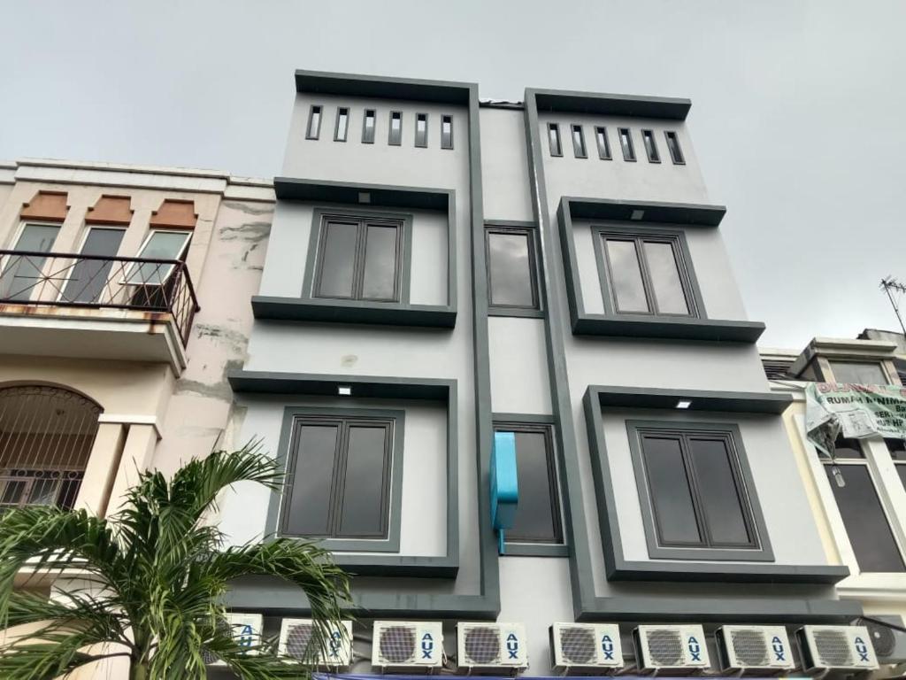 un edificio blanco con ventanas negras y una palmera en Amethyst cengkareng syariah en Yakarta