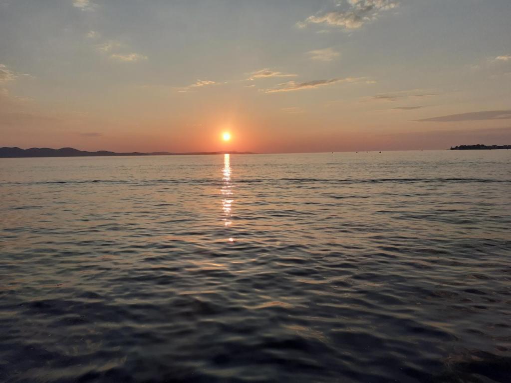 een zonsondergang boven het water met zonsondergang bij Sunset zadar in Zadar