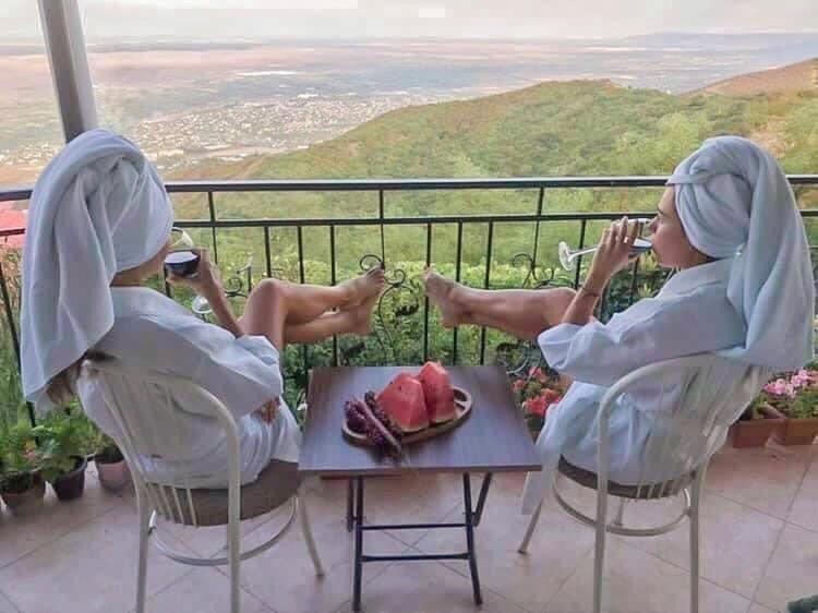 duas mulheres sentadas em cadeiras tirando fotos de uma mesa com comida em Zurabashvili Guest House em Signagi