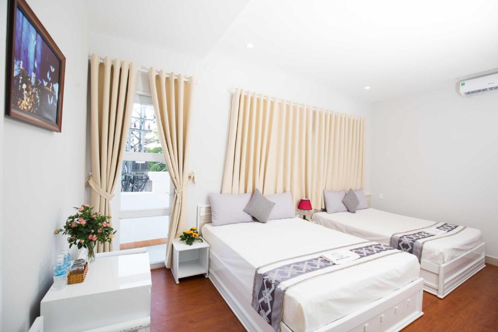 2 Betten in einem weißen Zimmer mit Fenster in der Unterkunft Nha Trang Pearl Hotel in Nha Trang