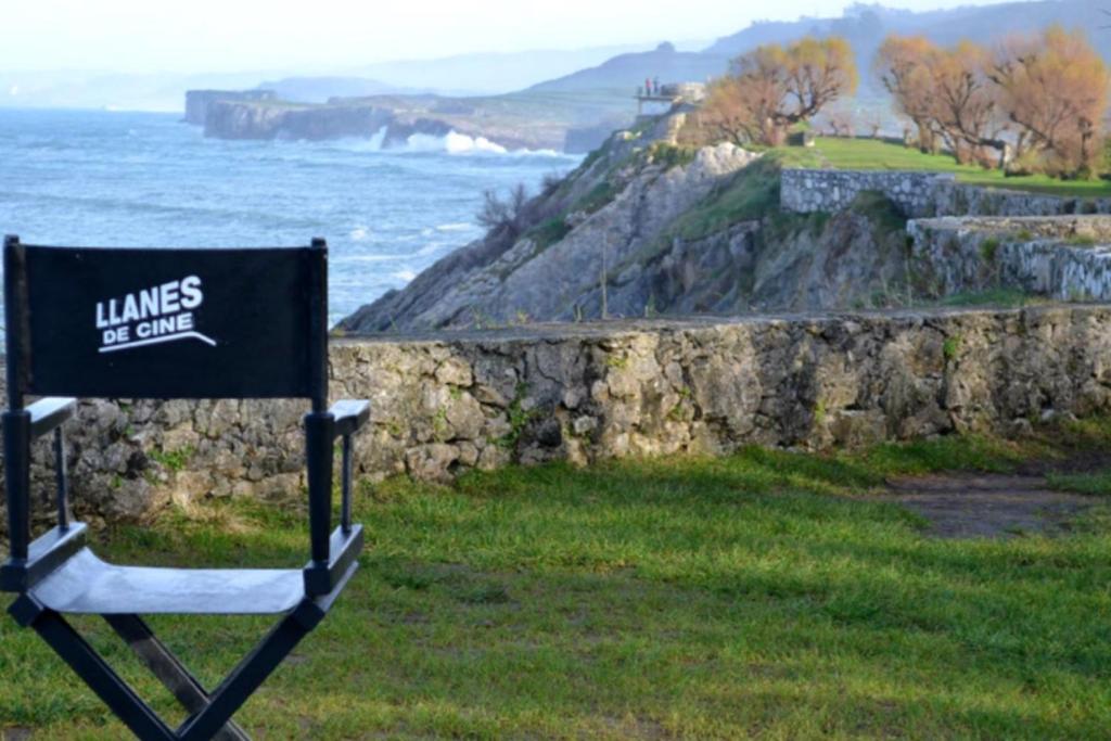 a sign sitting in the grass next to the ocean at Gran Pedroso de Llanes in Llanes