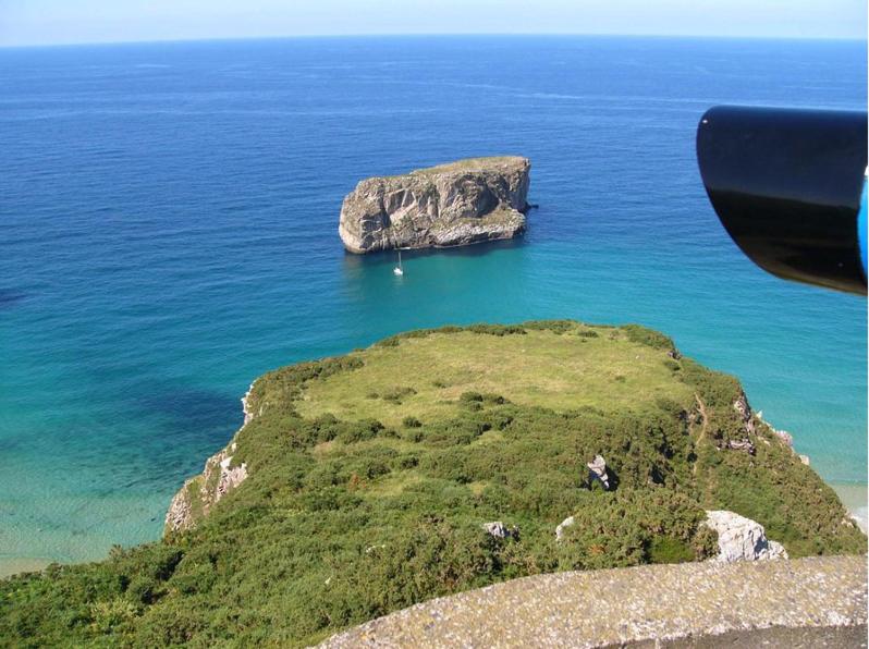 a small island in the ocean with a large rock at Gran Pedroso de Llanes in Llanes