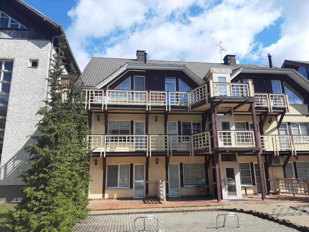 un edificio de apartamentos con balcones y un árbol en Viksvų apartamentai Juodkrantėje, en Juodkrantė