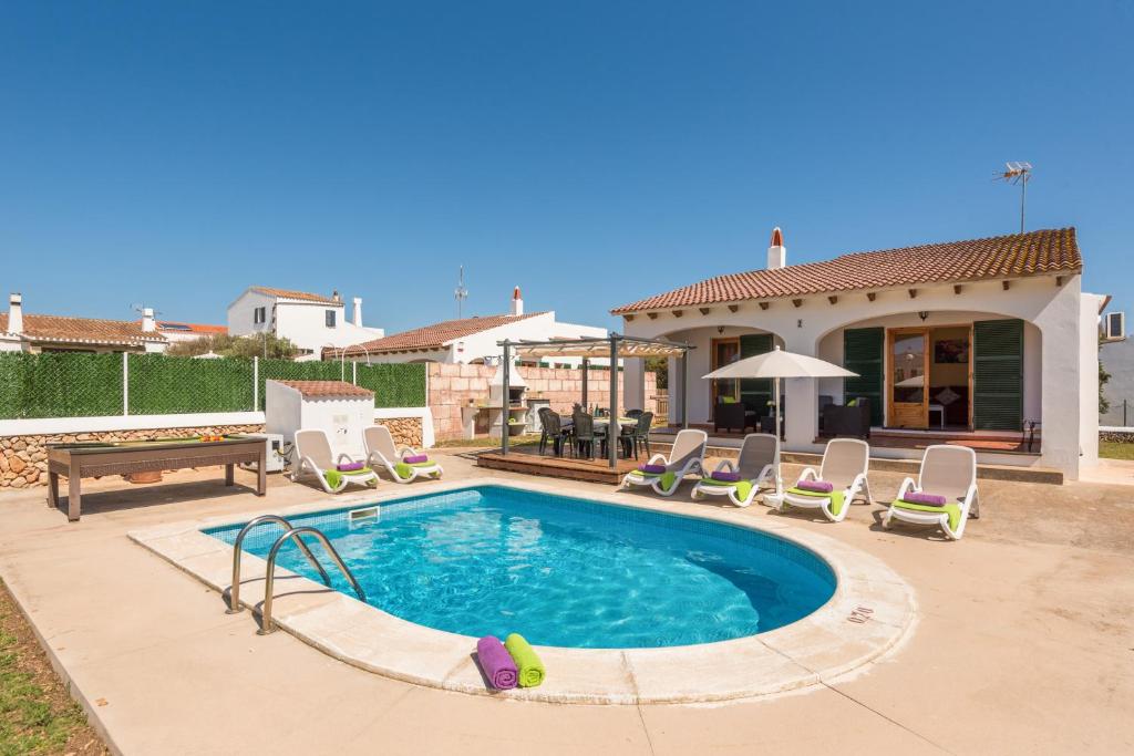 a swimming pool with chairs and a house at Villas Pomelo & Papaya in Cala en Blanes