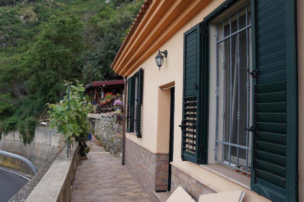 budynek z zielonymi okiennicami i chodnikiem w obiekcie Casa Vacanze Morselli w mieście Scilla
