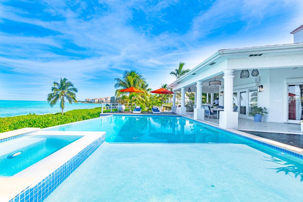 a swimming pool in front of a house with the ocean at Villa Northwinds - At Orange Hill - Private Pool in Nassau