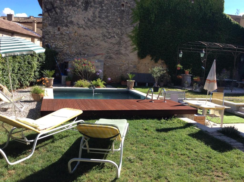 un patio con sillas, una mesa y una piscina en Villa des marronniers en Laudun