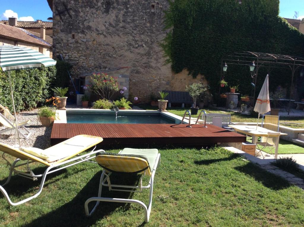 einen Garten mit Stühlen, einem Tisch und einem Pool in der Unterkunft Villa des marronniers in Laudun