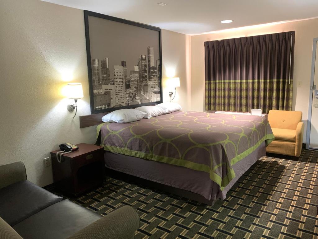 um quarto de hotel com uma cama e uma cadeira em Super 8 by Wyndham Baytown I-10 em Baytown