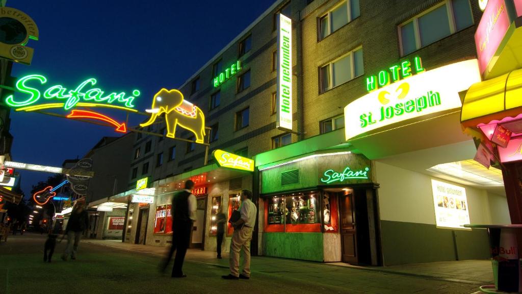 a group of people standing on a city street at night at St.Joseph Hotel Hamburg - Reeperbahn St.Pauli Kiez in Hamburg