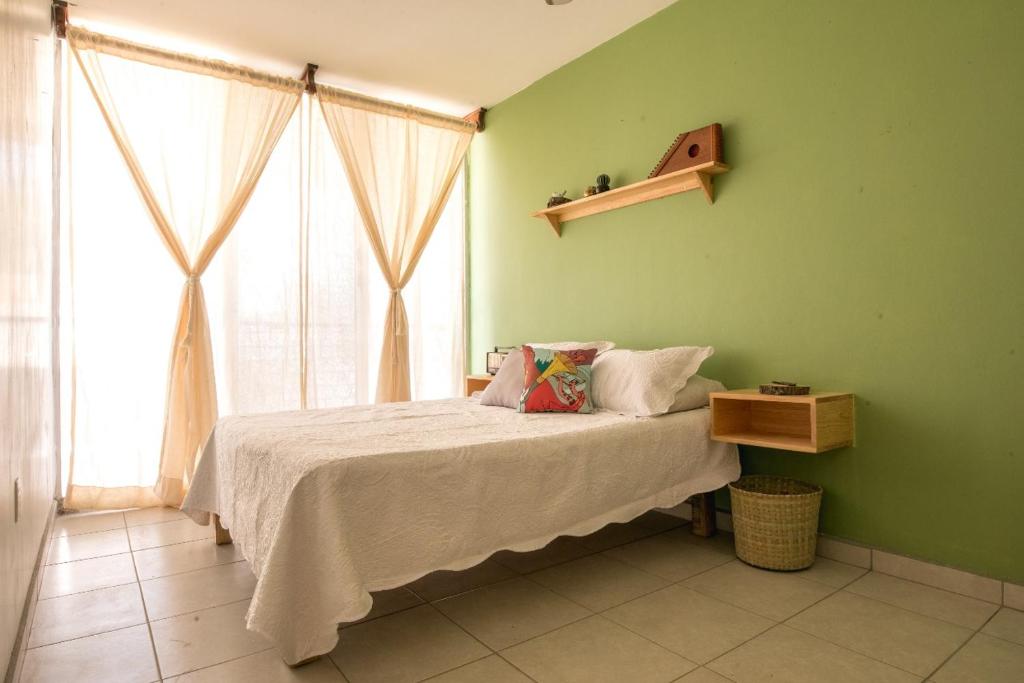 een slaapkamer met een bed met een groene muur bij Casa Matia in Guadalajara