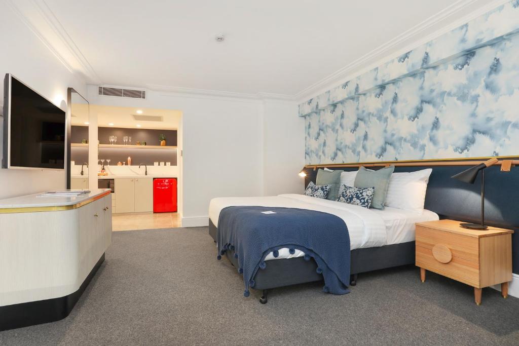 a bedroom with a bed with a blue and white wall at Coogee Bay Boutique Hotel in Sydney