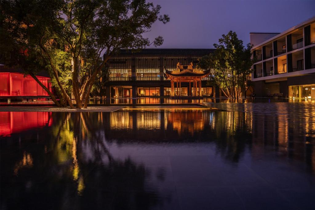 a building with a reflection in a body of water at Naera Hotel Xitang in Jiashan