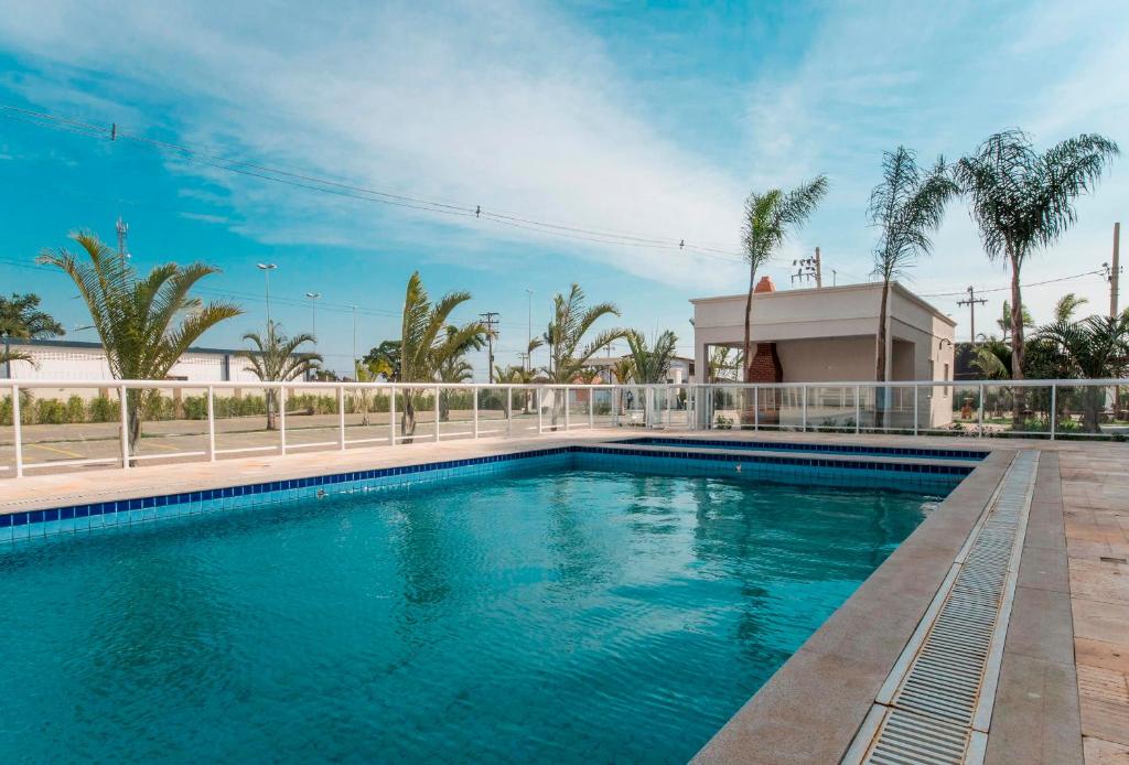 une piscine avec une clôture et des palmiers dans l'établissement Apt completo-Ar-TV-Portaria 24h-Piscina-Praia, à Campos dos Goytacazes
