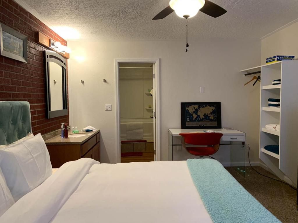 a bedroom with a white bed and a red chair at The Wing at Kingston East in Rexburg