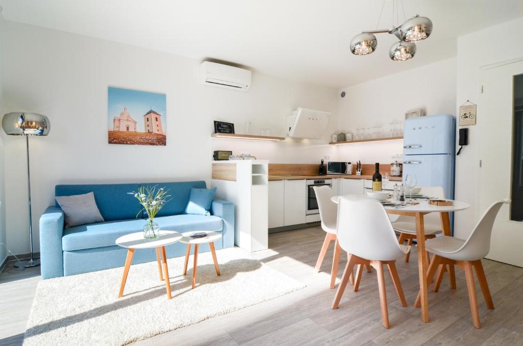 ein Wohnzimmer mit einem blauen Sofa, einem Tisch und Stühlen in der Unterkunft Apartmán Astrid in Mikulov