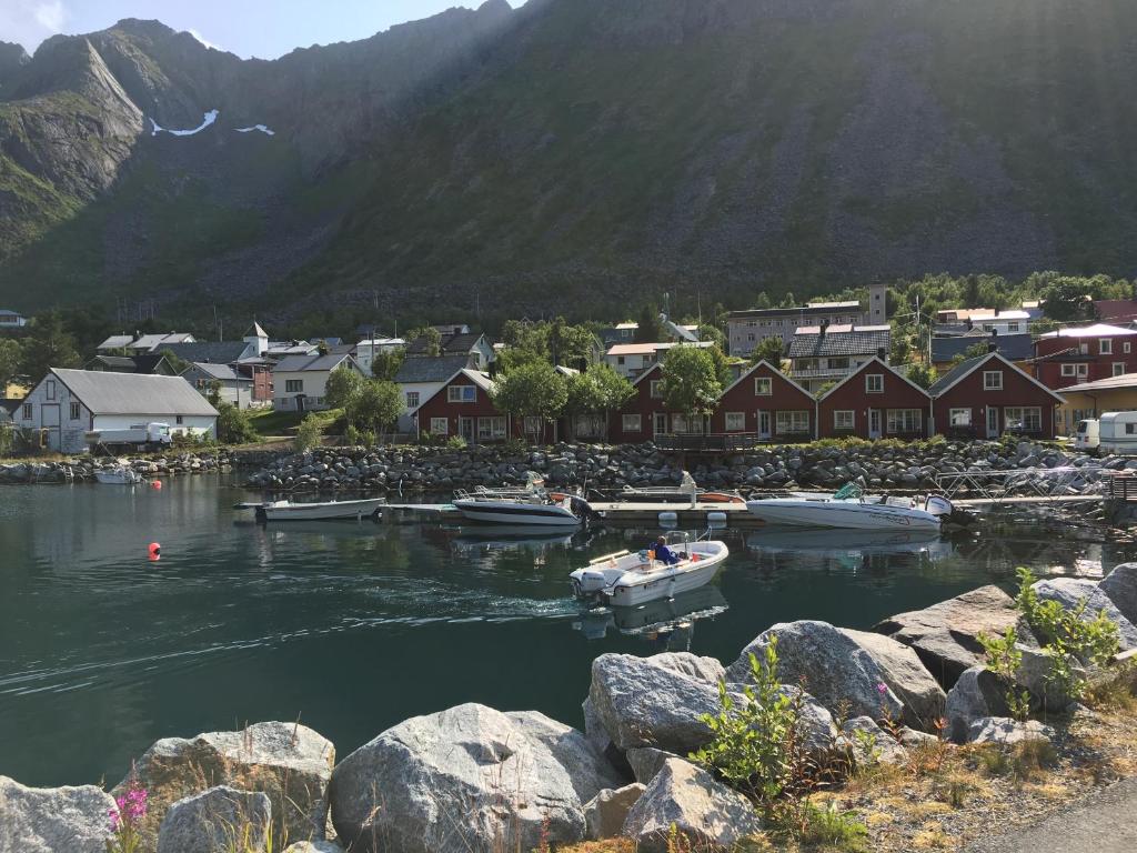 a small boat in a body of water with houses and mountains at Kaikanten Gryllefjord in Gryllefjord