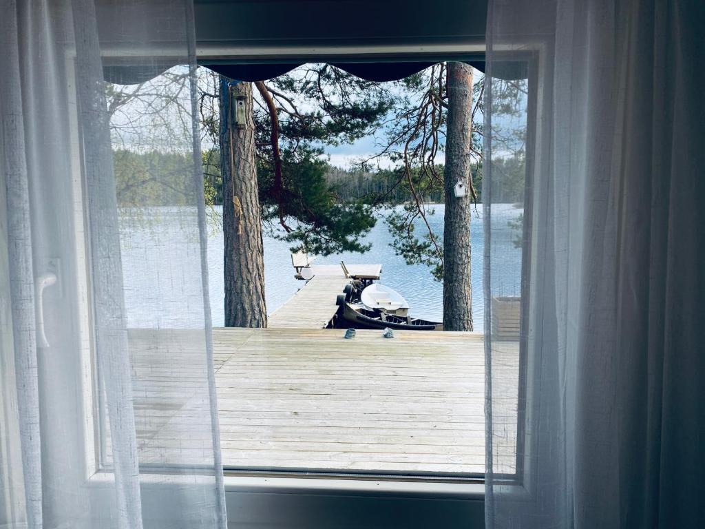 a window with a view of a wooden dock at Stuga Holmasjön in Vetlanda