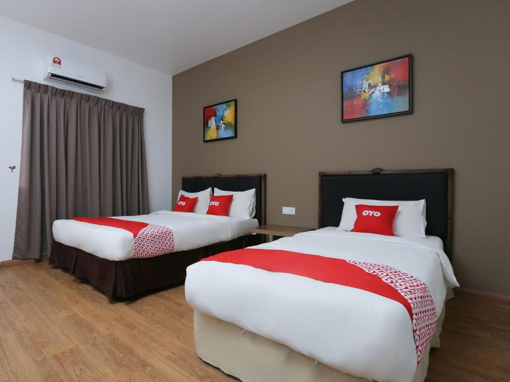 two beds in a hotel room with red pillows at OYO 89915 East Mount Hotel in Kukup