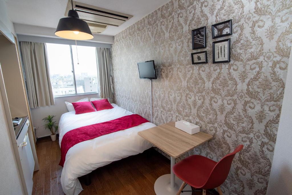 niewielka sypialnia z łóżkiem i stołem w obiekcie Vail sta Takenotsuka w Tokio