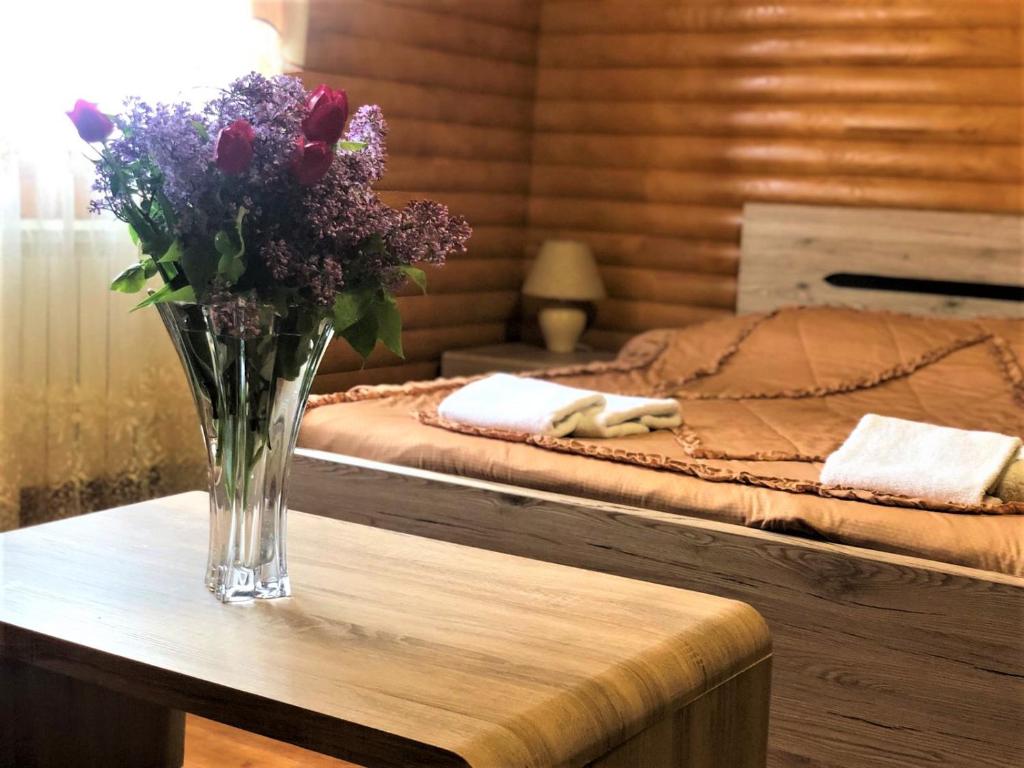 eine Vase mit Blumen auf einem Tisch in einem Schlafzimmer in der Unterkunft Parusa Maklaia in Baturyn