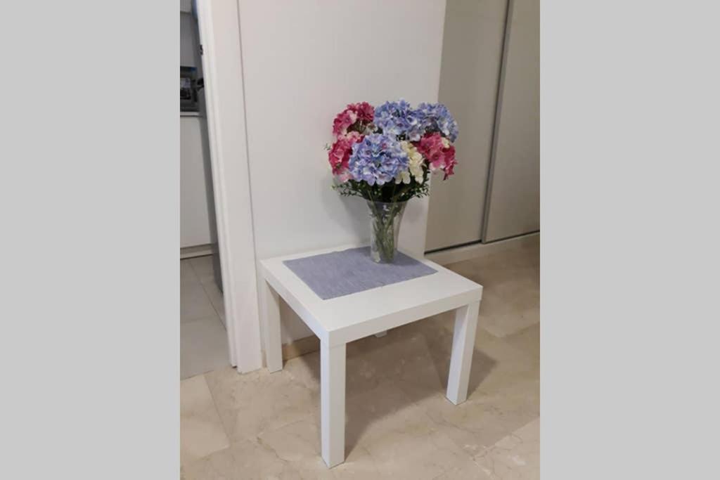 un vase de fleurs assis sur une table blanche dans l'établissement El Centro 15 (Verblijf aan de Costa), à Benidorm