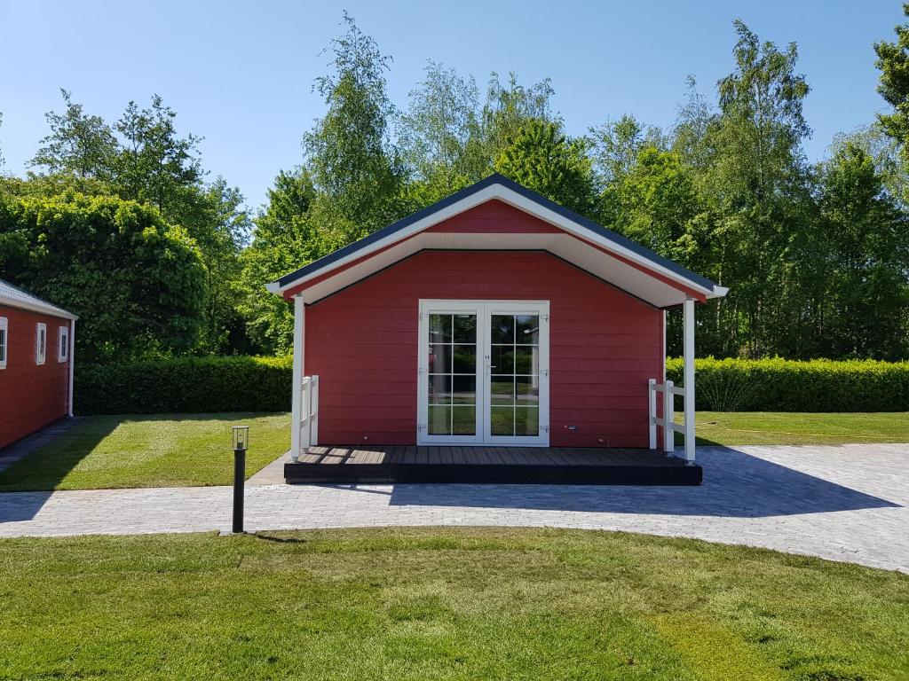 een rode schuur met een deur in een tuin bij De Bijsselse Enk, Noors chalet 11 in Nunspeet