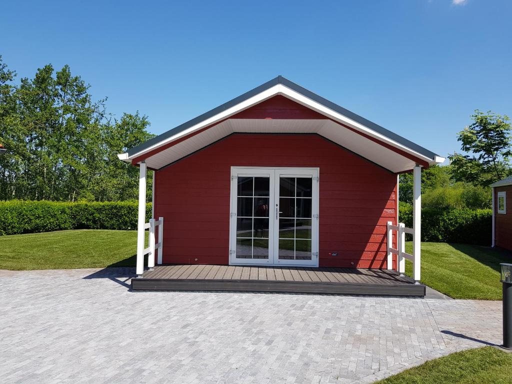 a small red shed with a wooden porch at De Bijsselse Enk, Noors chalet 9 in Nunspeet