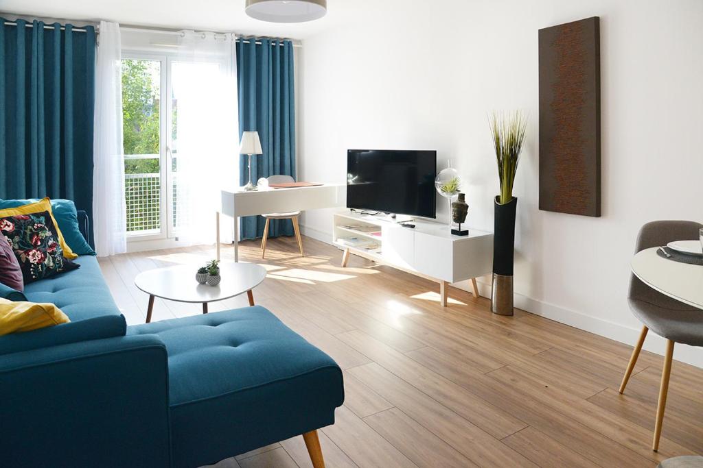 sala de estar con sofá azul y TV en Business Appart, en Tourcoing